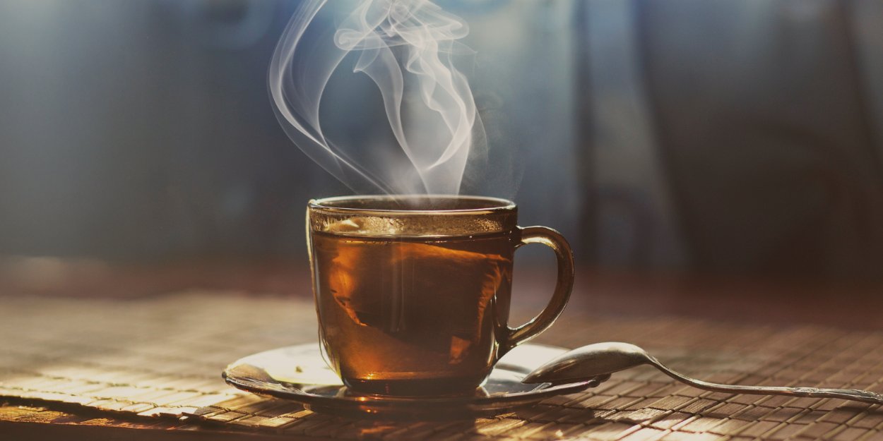 Steaming glass of tea on a table, representing herbal tea, green tea benefits, mint blends, and afternoon tea in Malta.