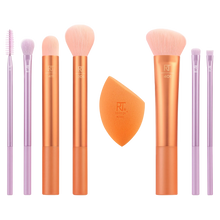 Load image into Gallery viewer, A set of Real Techniques makeup brushes and a sponge, with brushes featuring orange and purple handles, laid out on a white surface.