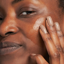 Load image into Gallery viewer, Close-up of a person applying cream to their face with a finger.