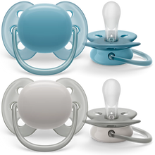 Load image into Gallery viewer, Two Philips Avent ultra soft pacifiers, one in blue and one in gray, designed for sensitive skin with a rounded shield to minimize pressure on the cheeks.