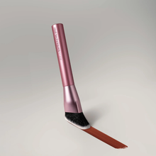 Load image into Gallery viewer, Close-up product image of the Real Techniques RT458 contour brush with a metallic pink handle and angled bristles. The brush is shown applying a smooth swipe of brown contour makeup against a soft neutral background.