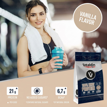 Load image into Gallery viewer, A square promotional banner featuring a woman in a gym setting with a white towel around her neck, holding a blue protein shaker. On the right, a circular badge reads "VANILLA FLAVOR." The bottom of the graphic includes a product bag and three icons specifying 21g Protein, No Added Sugars, and 6.7g BCAA content.
