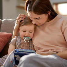 Load image into Gallery viewer, Toddler boy with Avent Ultra Air neutral pacifier sitting on mom’s lap while reading a book