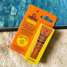 Load image into Gallery viewer, Dr. PAWPAW Lip Balm SPF 20 in orange packaging displayed beside a swimming pool and beach towel, showcasing moisturising lip care with sun protection.
