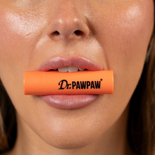 Load image into Gallery viewer, Close-up of a person holding the orange Dr. PAWPAW Mango Lip Balm Stick between their lips, showcasing the mango-scented lip care product.
