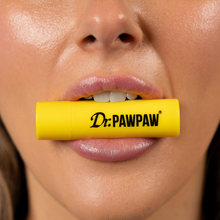 Load image into Gallery viewer, Close-up of a person holding the yellow Dr.PAWPAW Original Lip Balm Stick between their lips, showcasing the compact lip care product.