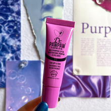Load image into Gallery viewer, Dr. PAWPAW Plumping Lip Oil 8ml in a purple tube held in front of a purple beauty-themed background, showcasing its hydrating lip care formula.