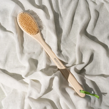 Load image into Gallery viewer, EcoTools bamboo bristle bath brush displayed on textured white linen fabric.