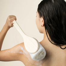 Load image into Gallery viewer, Person using the long-handled EcoTools loofah bath brush with soapy lather to exfoliate their back.