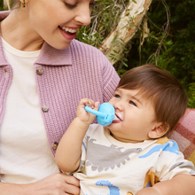 Load image into Gallery viewer, Mother holding baby using the Munchkin Baby Food Feeder in blue, safe silicone pouch for feeding soft solids from 4 months.