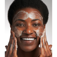 Load image into Gallery viewer, Close-up of a person smiling while applying NeoStrata Ultra Brightening Cleanser to their face, showing the creamy lather and healthy skin glow.