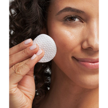Load image into Gallery viewer, A close-up of a person smiling and using a NeoStrata Smooth Surface Glycolic Peel pad on their cheek to improve skin texture.