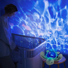 Load image into Gallery viewer, Pabobo Aqua Dream Turtle nightlight creating an immersive, blue ocean ripple projection on a nursery wall next to a crib, viewed by an adult.