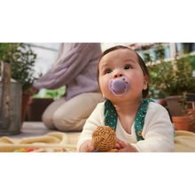 Load image into Gallery viewer, An infant wearing green overalls and using a lavender purple Philips Avent Ultra Soft soother (SCF091/43) while playing on a blanket.