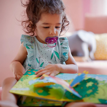 Load image into Gallery viewer, Toddler girl reading a book while using Philips Avent Ultra Air pacifier with 'Love' design