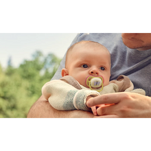 Load image into Gallery viewer, An infant being held outdoors while using a Philips Avent Ultra Air Nighttime soother with a butterfly design and glow-in-the-dark feature.