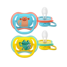 Load image into Gallery viewer, A 2-pack of Philips Avent Ultra Air soothers for 18m+, featuring a blue monkey design and a yellow frog design with large air holes for skin comfort.