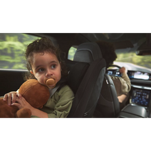 Load image into Gallery viewer, A toddler sitting in a car seat using a terracotta orange Philips Avent Ultra Soft soother while holding a plush toy during a car ride.
