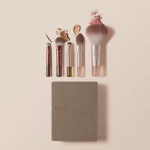 Load image into Gallery viewer, Real Techniques travel makeup brush set displayed flat with five mini brushes, makeup swatches, and closed mirrored compact case.