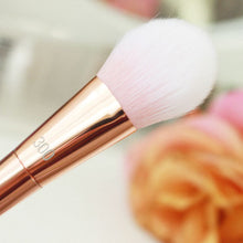 Load image into Gallery viewer, Makeup brush with rose gold handle and pink bristle on a blurred floral background