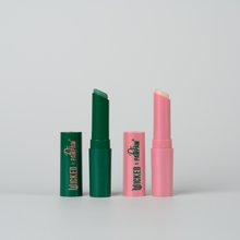 Load image into Gallery viewer, WICKED x Dr. PAWPAW Enchanting and Glimmer Lip Balm Sticks displayed open alongside their green and pink caps against a light grey background.