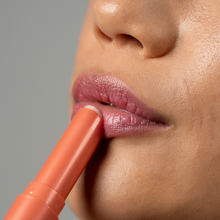 Load image into Gallery viewer, Close-up of WICKED x Dr. PAWPAW Glimmer Lip Balm in pink packaging being applied to the lips, showcasing its moisturising formula and shimmering finish.