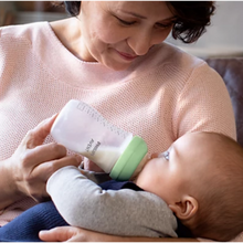 Load image into Gallery viewer, A woman in a pink sweater smiles warmly while bottle-feeding an infant with a Philips Avent baby bottle.