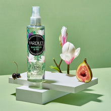 Load image into Gallery viewer, Yardley London Magnolia & Fig Moisturising Body Mist (200ml) lifestyle display with fresh magnolia and fig, featuring its 97% natural, vegan formula in a commemorative 250th-anniversary bottle.
