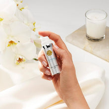 Load image into Gallery viewer, Hand applying or holding the Exuviance Professional Total Correct Eye cream dispenser, emphasizing professional-grade luxury and its small size for targeted use around the eyes.