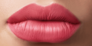 Close-up of a woman's lips adorned with vibrant pink lipstick, highlighting their shape and color.