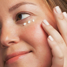 Load image into Gallery viewer, Close-up of a woman applying cream under her eye with a finger.
