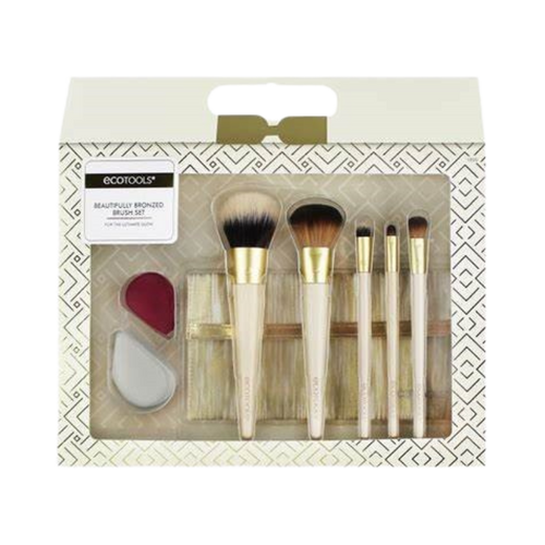 A set of ECO TOOLS makeup brushes with bronzed handles and bristles, displayed in an organized fashion within a white box with gold geometric patterns.