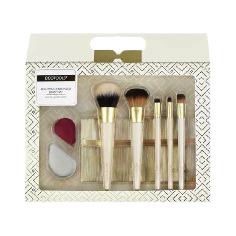 A set of ECO TOOLS makeup brushes with bronzed handles and bristles, displayed in an organized fashion within a white box with gold geometric patterns.
