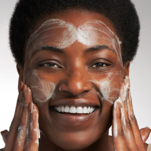 Load image into Gallery viewer, Woman applying cream to her face with a neutral background
