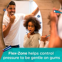 Load image into Gallery viewer, A father and daughter standing in front of a bathroom mirror, smiling while brushing their teeth together, with text below explaining that the Flex-Zone helps control pressure to be gentle on gums.

