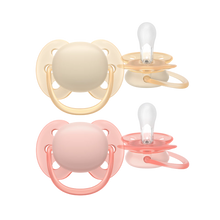 Load image into Gallery viewer, A set of two baby pacifiers, one in beige and one in pink, shown from both front and side angles against a black background.

