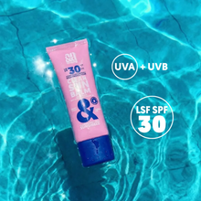 Load image into Gallery viewer, The pink Clear Sun Balm tube floating in pool water, emphasizing its UVA, UVB, and SPF 30 protection.
