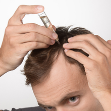 Load image into Gallery viewer, Man applying Crescina HFSC Transdermic treatment directly to his scalp using a precision ampoule applicator while parting his hair.
