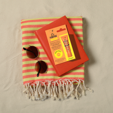 Load image into Gallery viewer, Dr. PAWPAW Lip Balm SPF 20 displayed with sunglasses, a striped beach towel and a red book, highlighting lip sun protection for summer activities.
