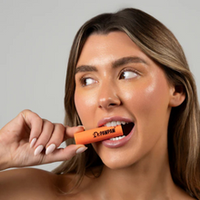 Load image into Gallery viewer, Light-skinned model applying Dr.PAWPAW Mango Lip Balm Stick playfully to lips
