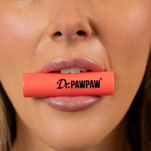 Load image into Gallery viewer, Close-up of a person holding the coral Dr. PAWPAW Watermelon Lip Balm Stick between their lips, showcasing the watermelon-scented lip care product.
