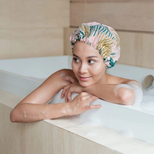 Load image into Gallery viewer, Woman wearing the EcoTools tropical print shower cap relaxing in a bubble bath while keeping her hair dry.
