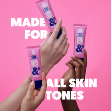 Load image into Gallery viewer, Multiple hands of varying skin tones holding Clear Sun Balm tubes to show it leaves no white cast.

