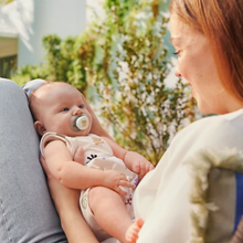 Load image into Gallery viewer, A parent holding a baby outdoors who is using a Philips Avent Ultra Air pacifier, highlighting the lightweight and breathable design for daily use.
