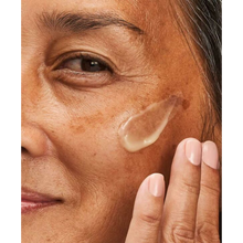 Load image into Gallery viewer, A close-up lifestyle image of a person with mature skin applying a swatch of NeoStrata Hyaluronic Luminous Lift cream to their cheek. The person is smiling slightly as they prepare to blend the product.
