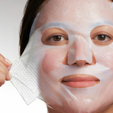 Load image into Gallery viewer, A close-up lifestyle image of a person applying a NeoStrata Restore Pure Hyaluronic Acid Biocellulose Mask. The translucent, textured sheet mask is being smoothed onto the face, showing a close fit around the eyes, nose, and mouth.
