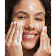 Load image into Gallery viewer, Close-up of a smiling woman applying NeoStrata Foaming Glycolic Wash to her face, showing the rich lather and exfoliating cleansing process.

