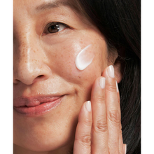 Load image into Gallery viewer, Close-up of a smiling person with freckles applying NeoStrata Resurface High Potency Cream to their cheek, with text highlighting its use for fine lines, wrinkles, and uneven skin tone.
