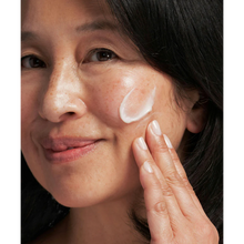 Load image into Gallery viewer, A person smiling while applying NeoStrata treatment cream to address visible sun spots and freckles.
