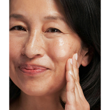Load image into Gallery viewer, A person smiling while applying NeoStrata Tri-Therapy Lifting Serum to address visible sun spots and uneven skin tone.
